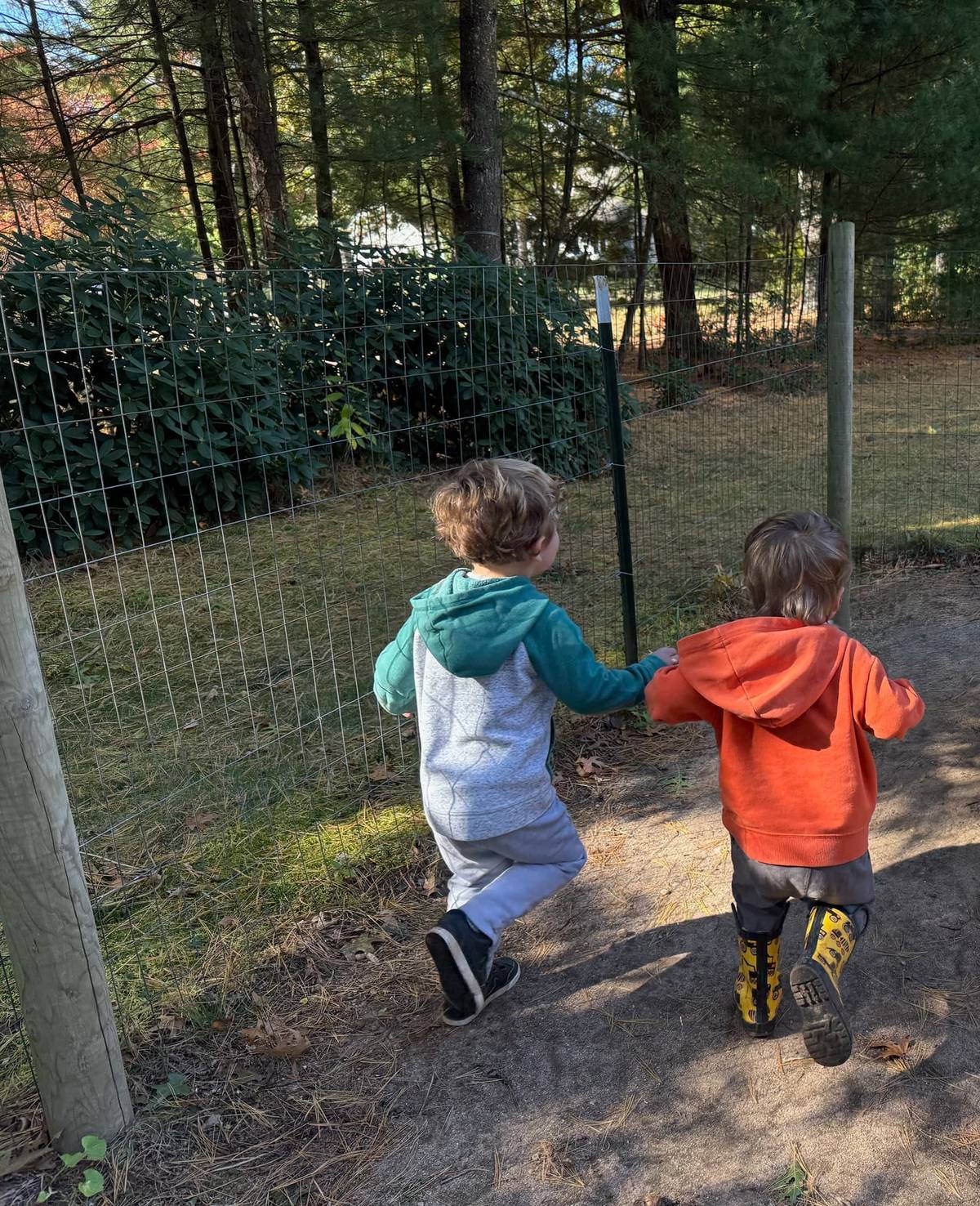 Two children walking along the fenced outdoor area at Ms Melody's Childcare
